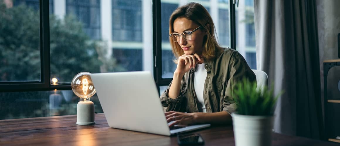 Young woman wearing glasses working on laptop.