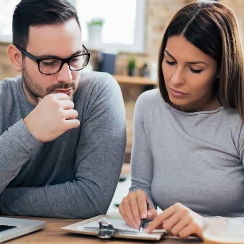 A couple looking at papers in a house, potentially discussing documents related to homeownership or a real estate purchase.