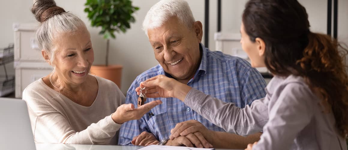 Excited Senior Husband And Wife Receive Keys In Realtor Office