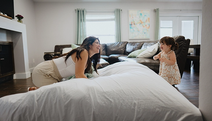 Woman on floor bed playing with small child.