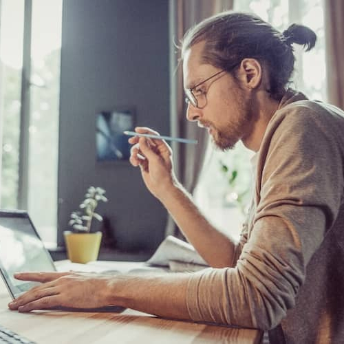 Man with bun working at home office.