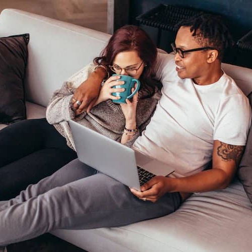 Image of couple relaxing on couch and reviewing credit scores.