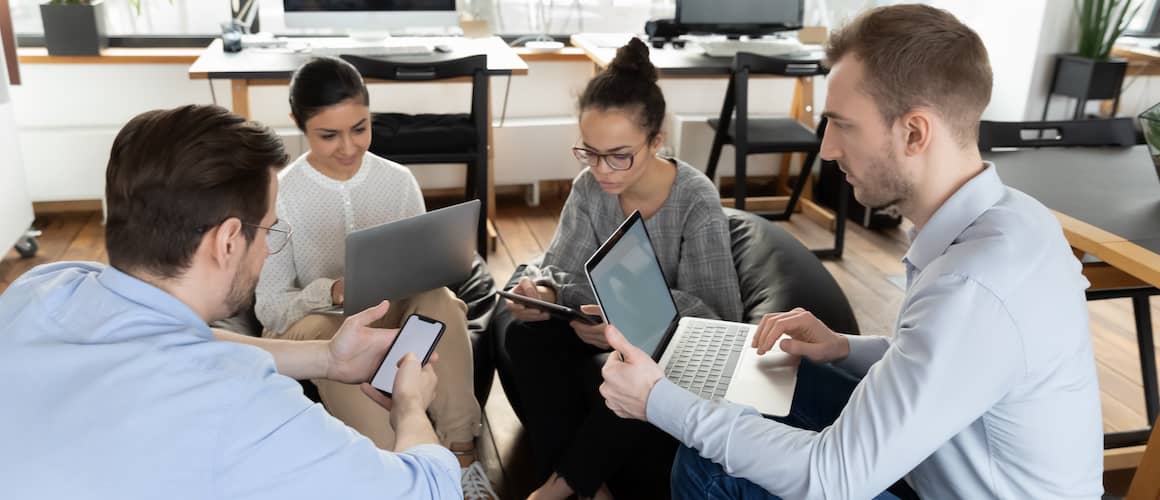 Coworkers on different devices sitting in a circle.