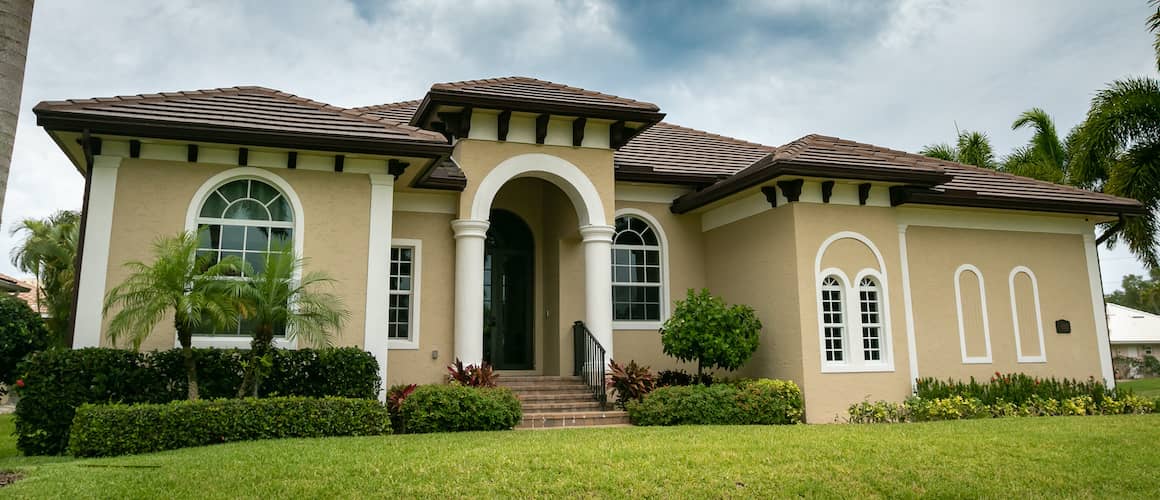 A yellow terracotta home with a brown tile roof and white trim, showcasing unique architectural features.