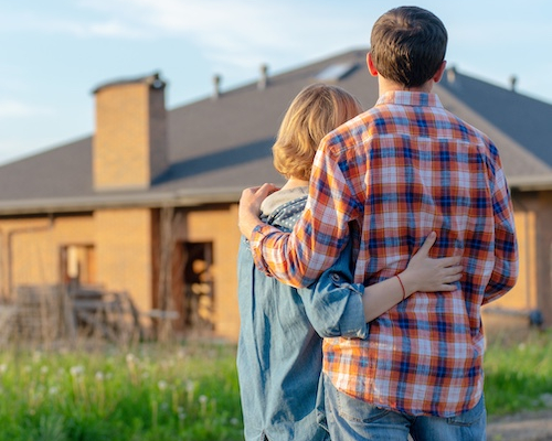 Couple embracing while looking at home.