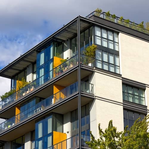 High rise condo with balconies filled with plants and a green roof.