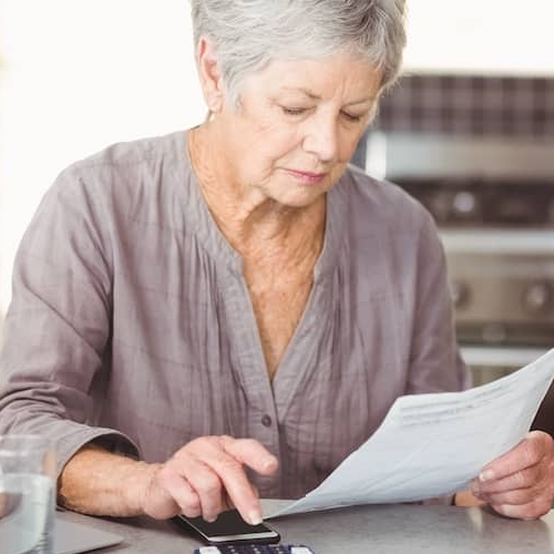 Senior woman engaged in financial tasks, possibly related to mortgage or property planning.