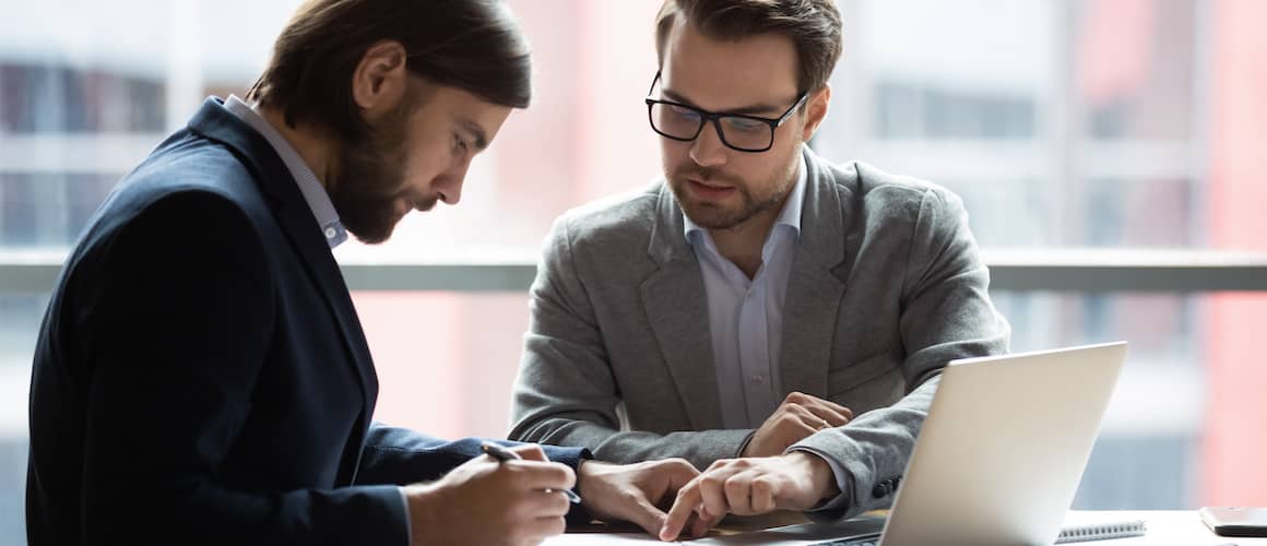 Focused young businessman signing and looking at papers with a lawyer.