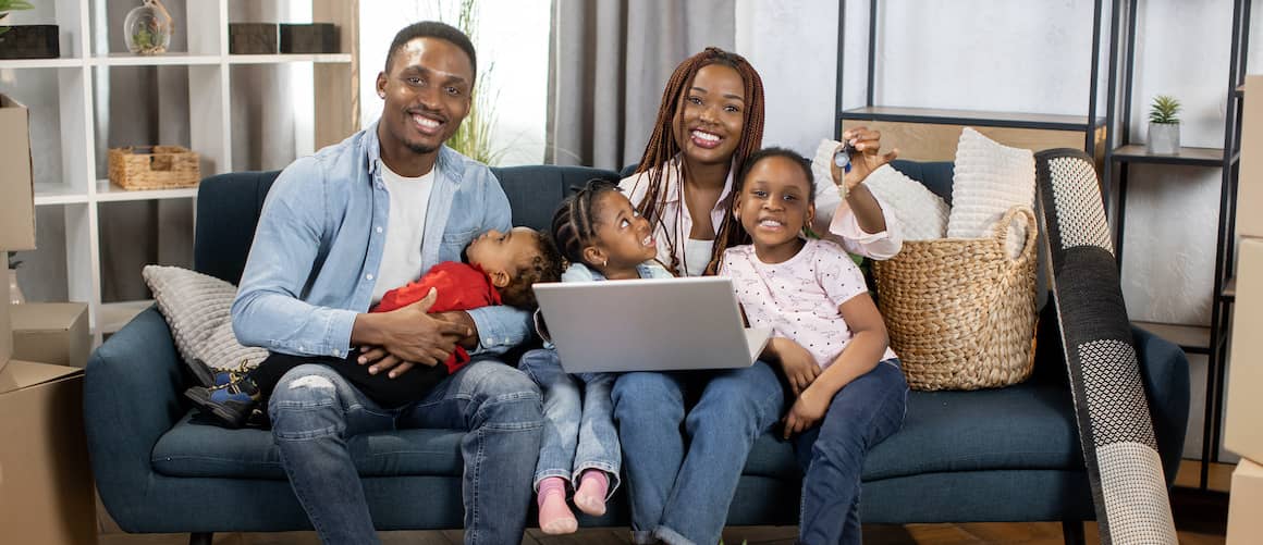 An African American family holding new keys, symbolizing the purchase or acquisition of a new home.