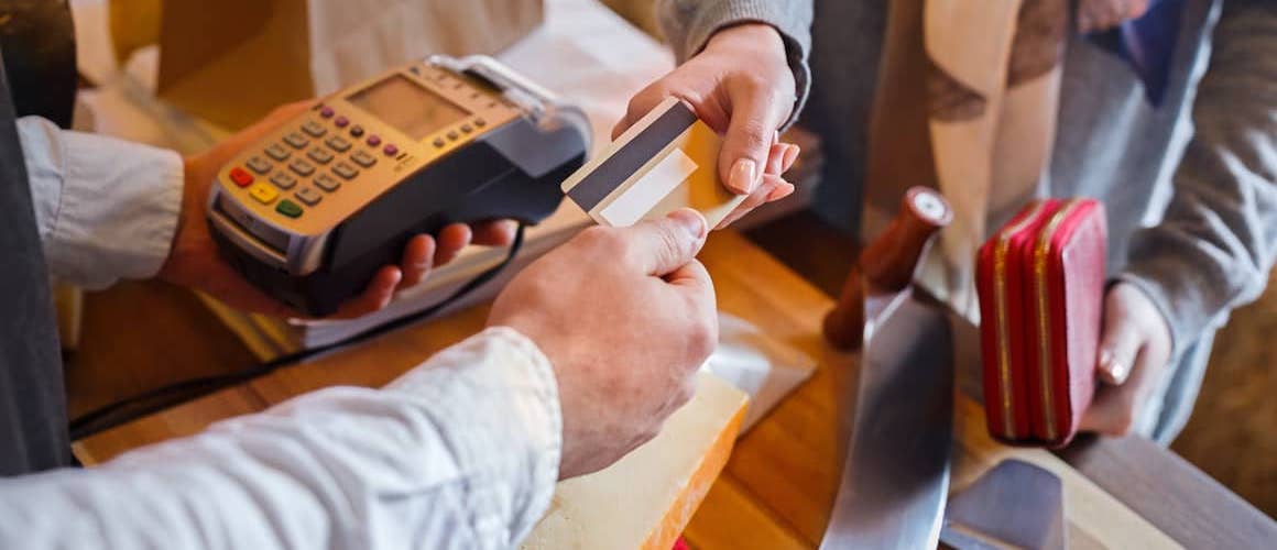 Customer paying for order of cheese at counter with credit card.