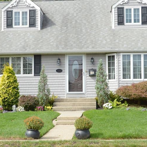 Exterior view of a suburban home with a well-manicured lawn and blue sky.