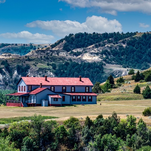 Large, rural home in Medora, North Dakota against a backdrop of the mountains.