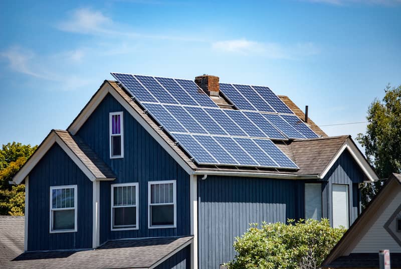 Grey single family home with solar panels on the roof.