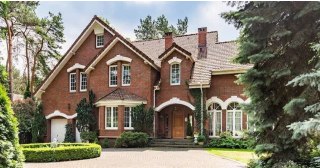 A large red brick home with a circle drive and landscaped yard