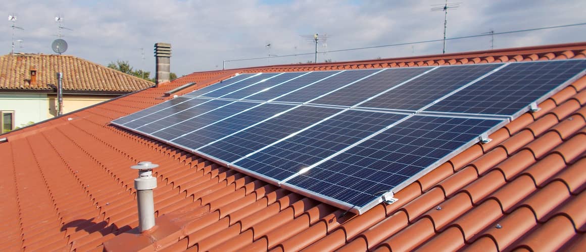 Solar panels on red roof in daylight.