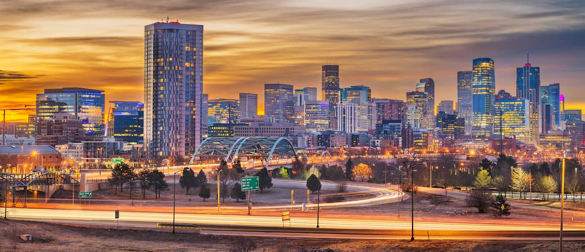 RHB Assets From IGX: Downtown Denver at sunset, with city skyline and mountains in the background.