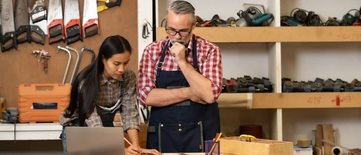 Woman describing plans for carpentry design to man who focuses intently.