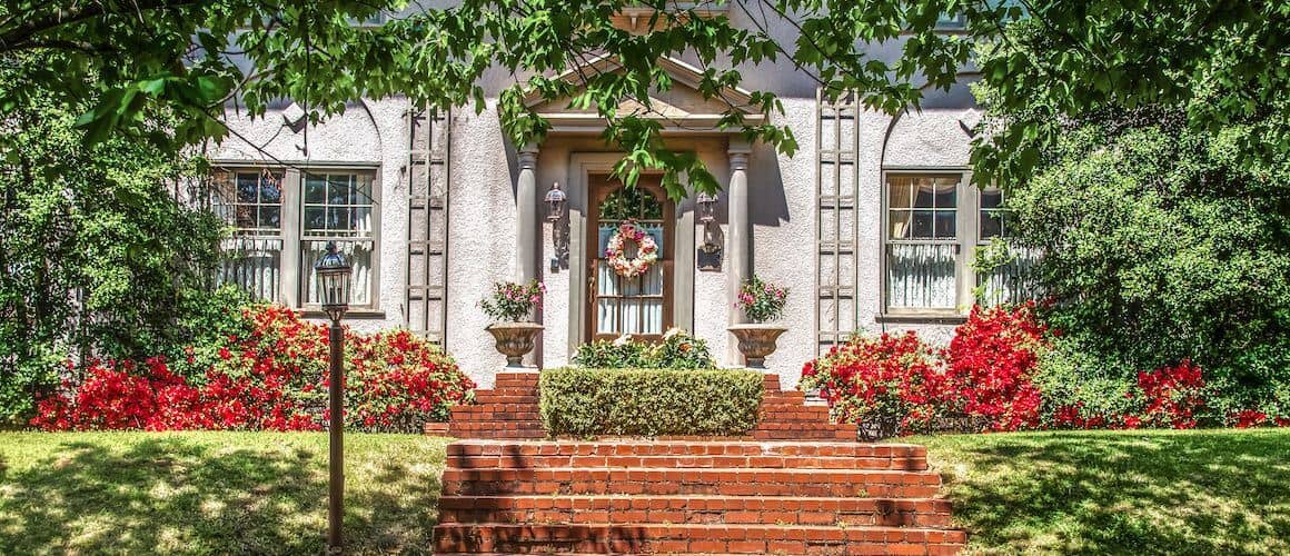 Large regal brick home with white columns and stone stairway.