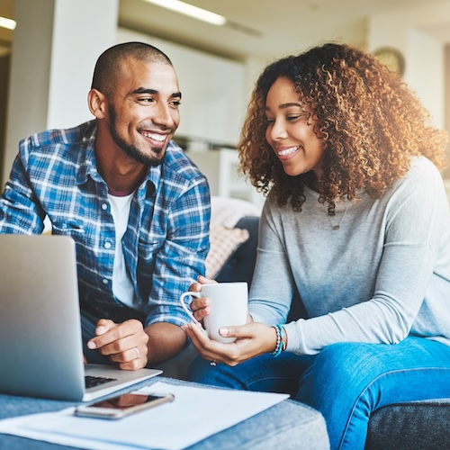 Young couple laughing together while looking at computer and planning a budget together.