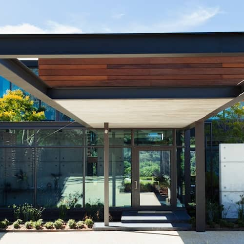 Contemporary home with wood panelled exterior and glass floor to ceiling windows.