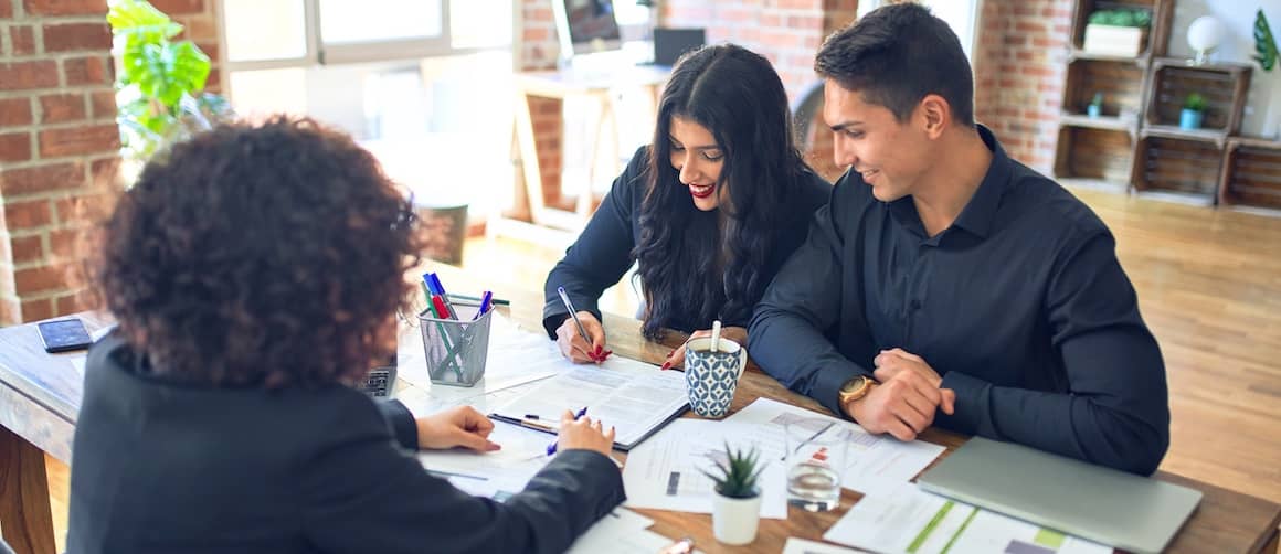 Young couple applying for a mortgage, smiling.