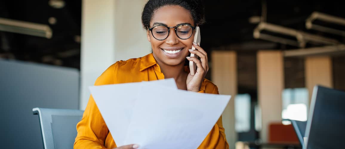 A woman on the phone reviewing a document, potentially related to financial or property matters.