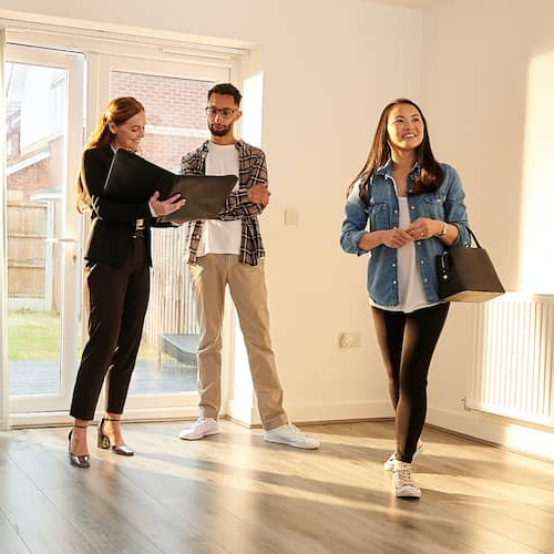A realtor showing a property to a couple and describing its features.