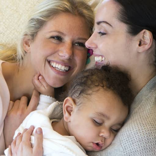 A mother and her baby resting together on a cozy couch.