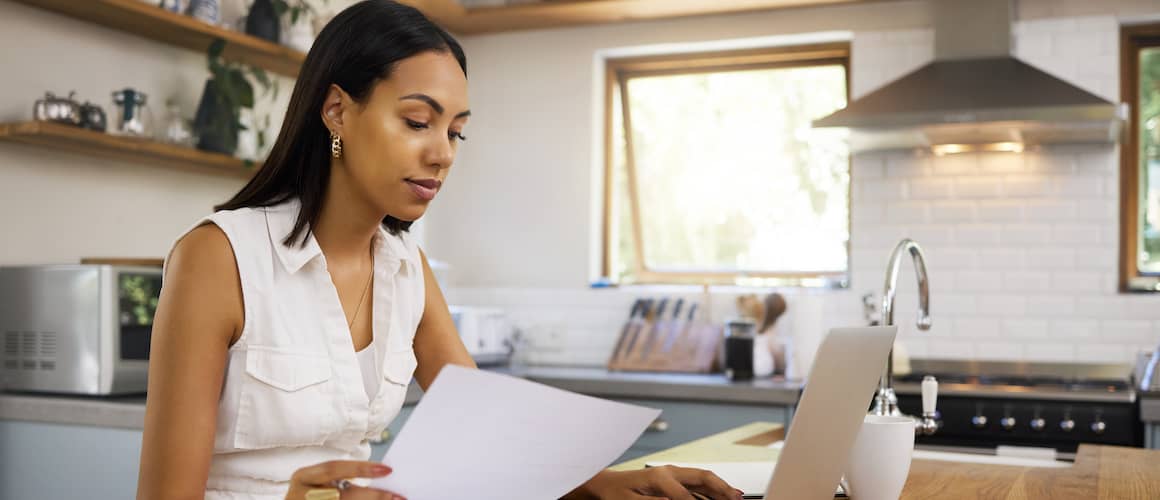 Young woman working from home in her kitchen on a laptop.