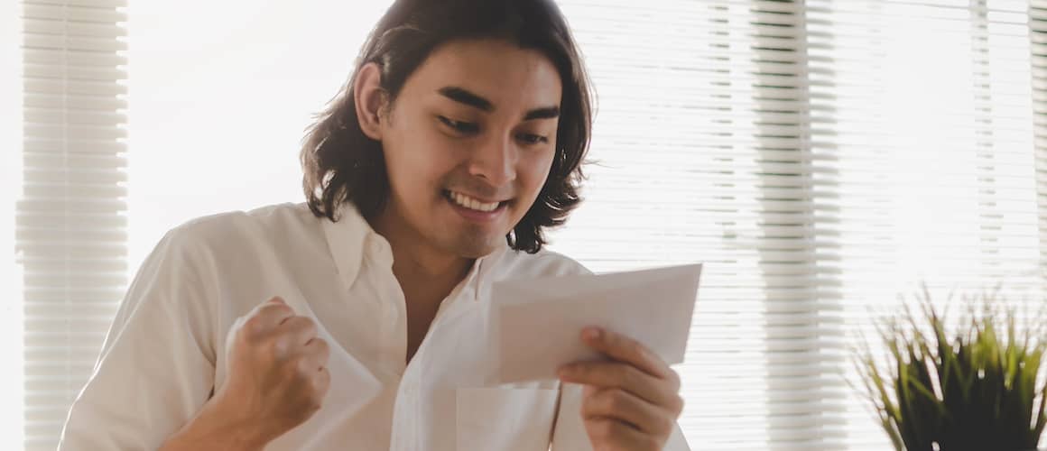 Young man holding mail and smiling.