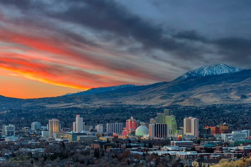 City of Reno, in Nevada, seen from afar with mountains behind it at dusk.