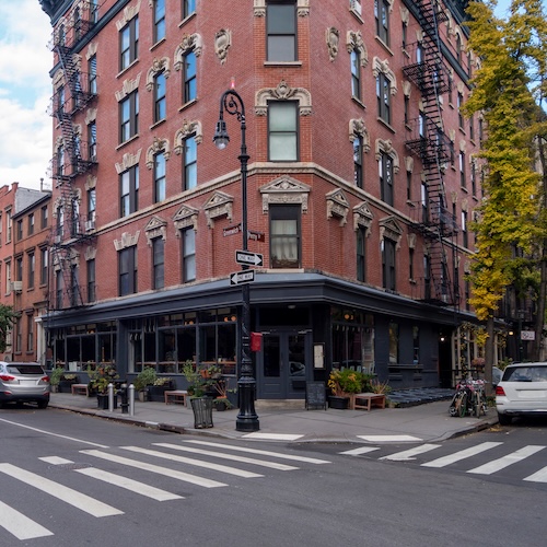 NYC street corner with old-fashioned brick apartment building.