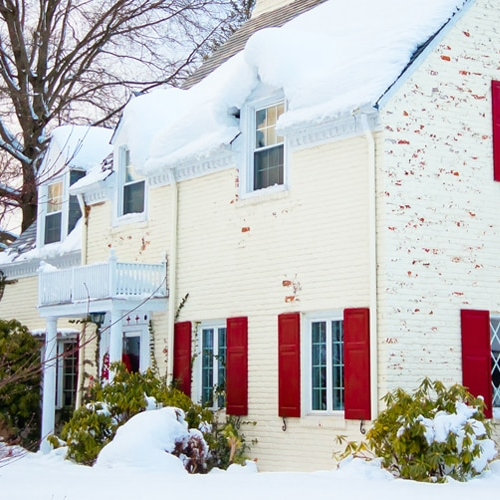 A white brick house in winters under snowy weather.