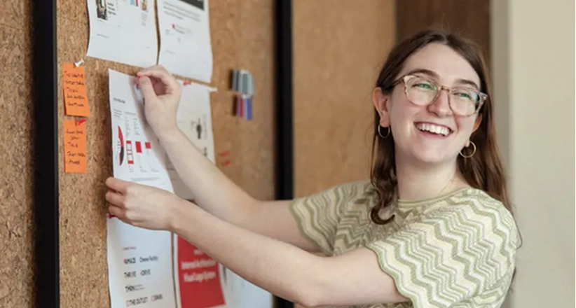 A person pins an item onto a bulletin board.