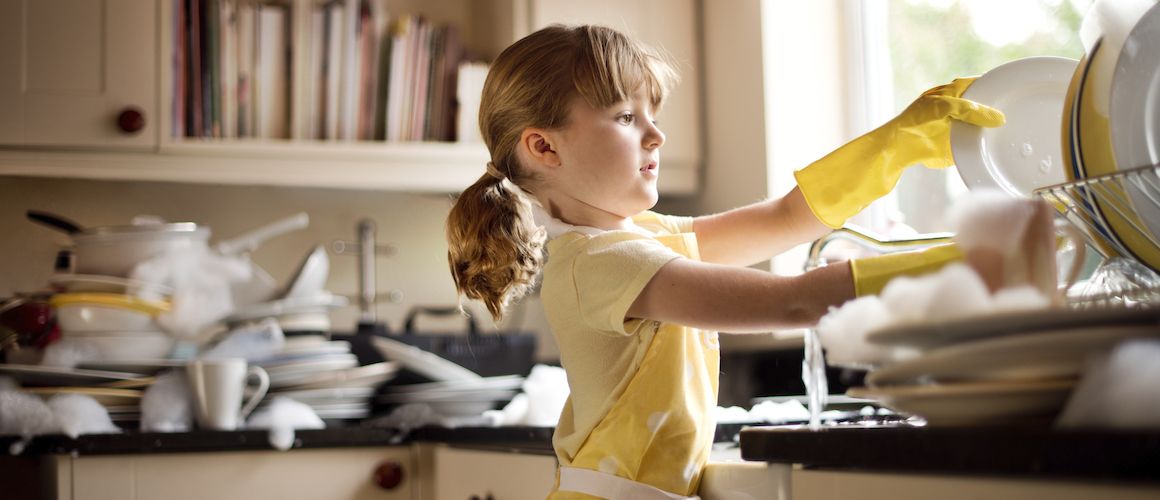 Young child washing dishes.