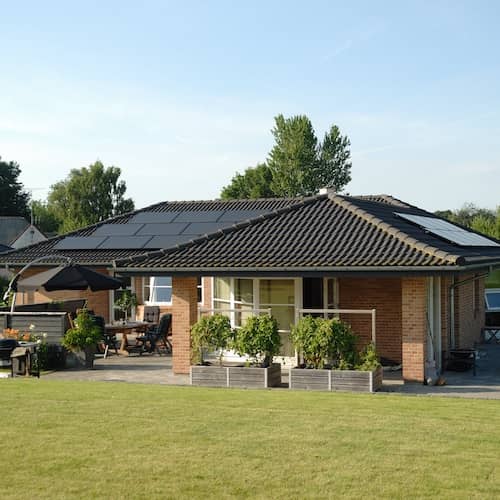 Energy efficient ranch style home with solar panels and raised bed gardens.