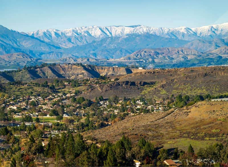 Distant view of Thousand Oaks, California, with large mountains and many trees.