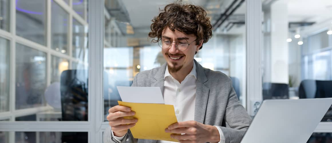 Happy businessman reading mail in his office.