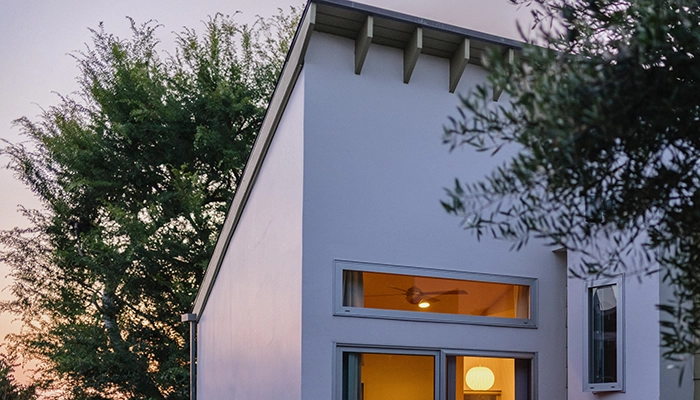 White house with warm interior light and small outdoor porch.