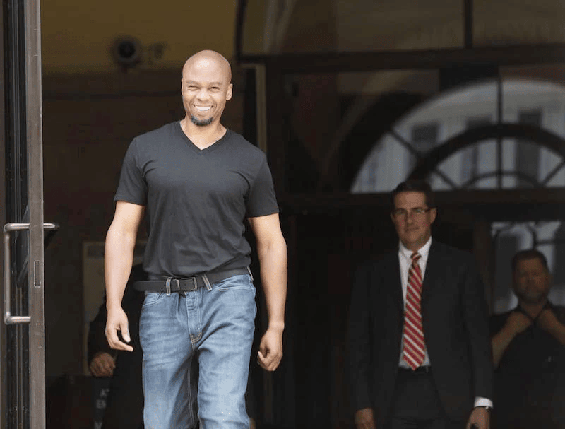 Man smiling while walking out of courthouse. 