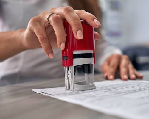 An individual stamping a document with what appears to be a notary stamp.