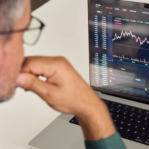 Man in suit reviewing stock market charts and numbers.