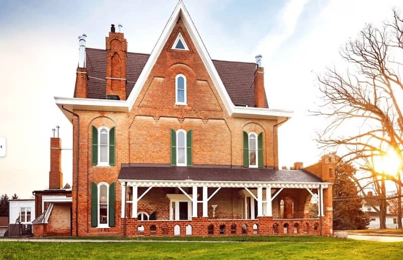 Historical brick home with pitched roof and covered front porch.