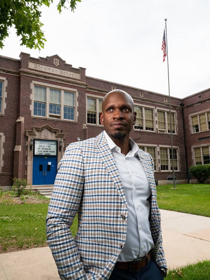 Man standing in front of a brick school building.