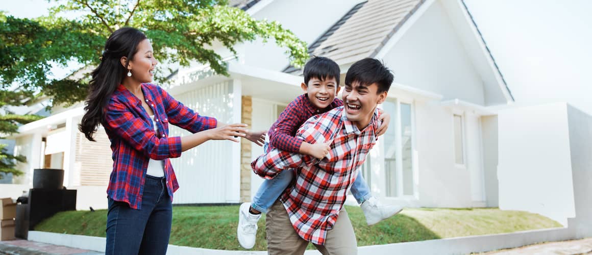 An Asian family enjoying family moments outside a white house.