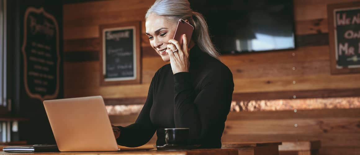 Businesswoman at a cafe making a phone call, potentially discussing business or financial matters.