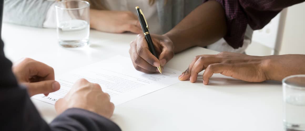 A man signing a home document with a broker, depicting a real estate transaction.