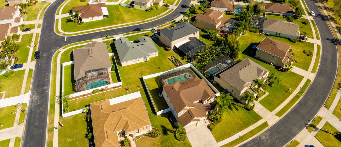 RHB Assets From IGX: An aerial view of a suburban neighborhood with green lawns and trees.