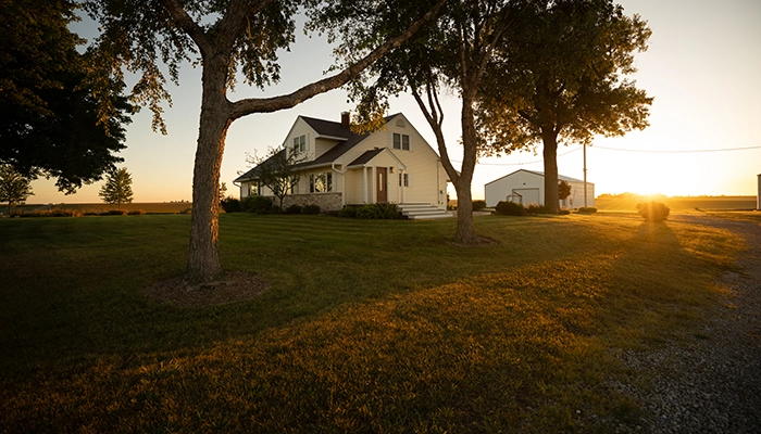 Beige house with golden sunlight falling over large lawn.