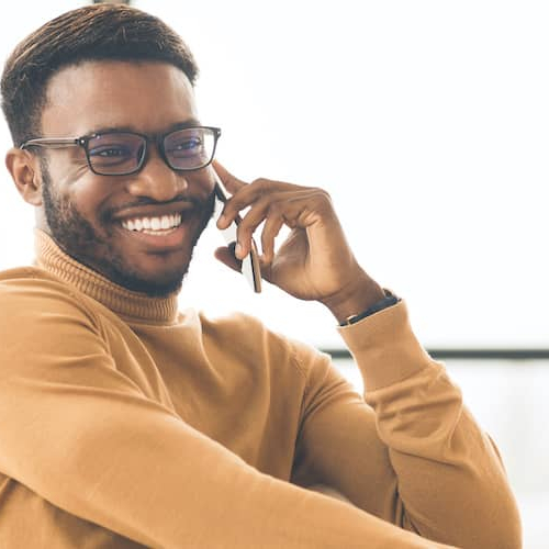 A black man on the phone, expressing happiness or contentment during a conversation.